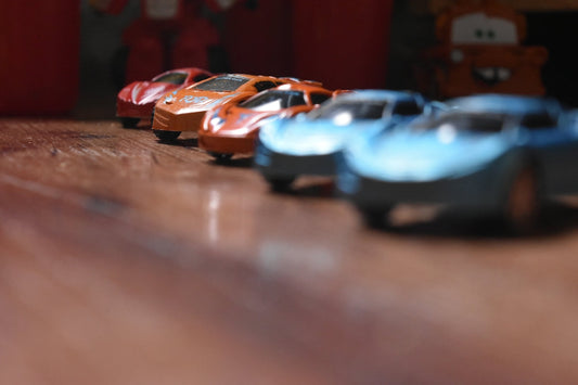 a row of toy cars sitting on top of a wooden floor