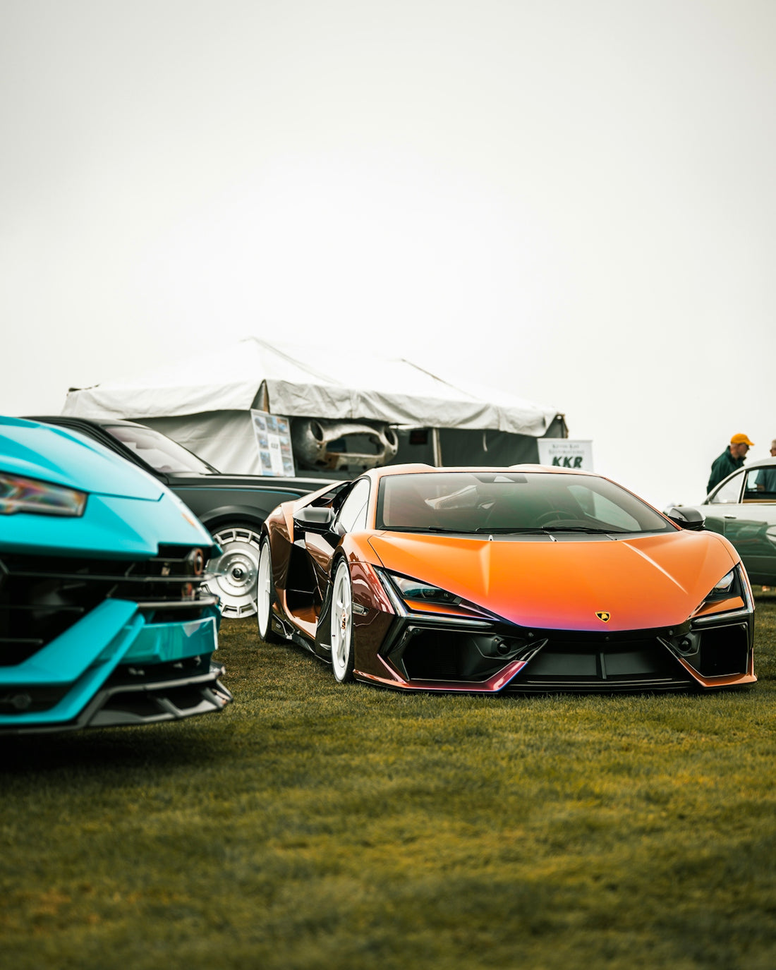 Three luxury sports cars parked on green grass