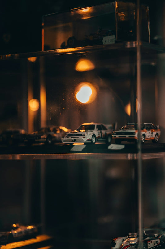 Die-cast model cars displayed in a glass cabinet.