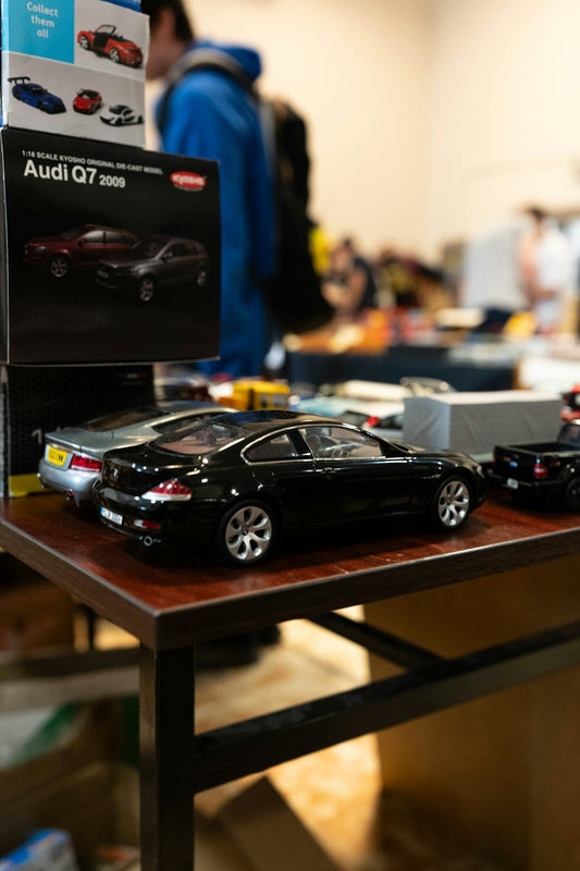 A black model car displayed on a wooden table.