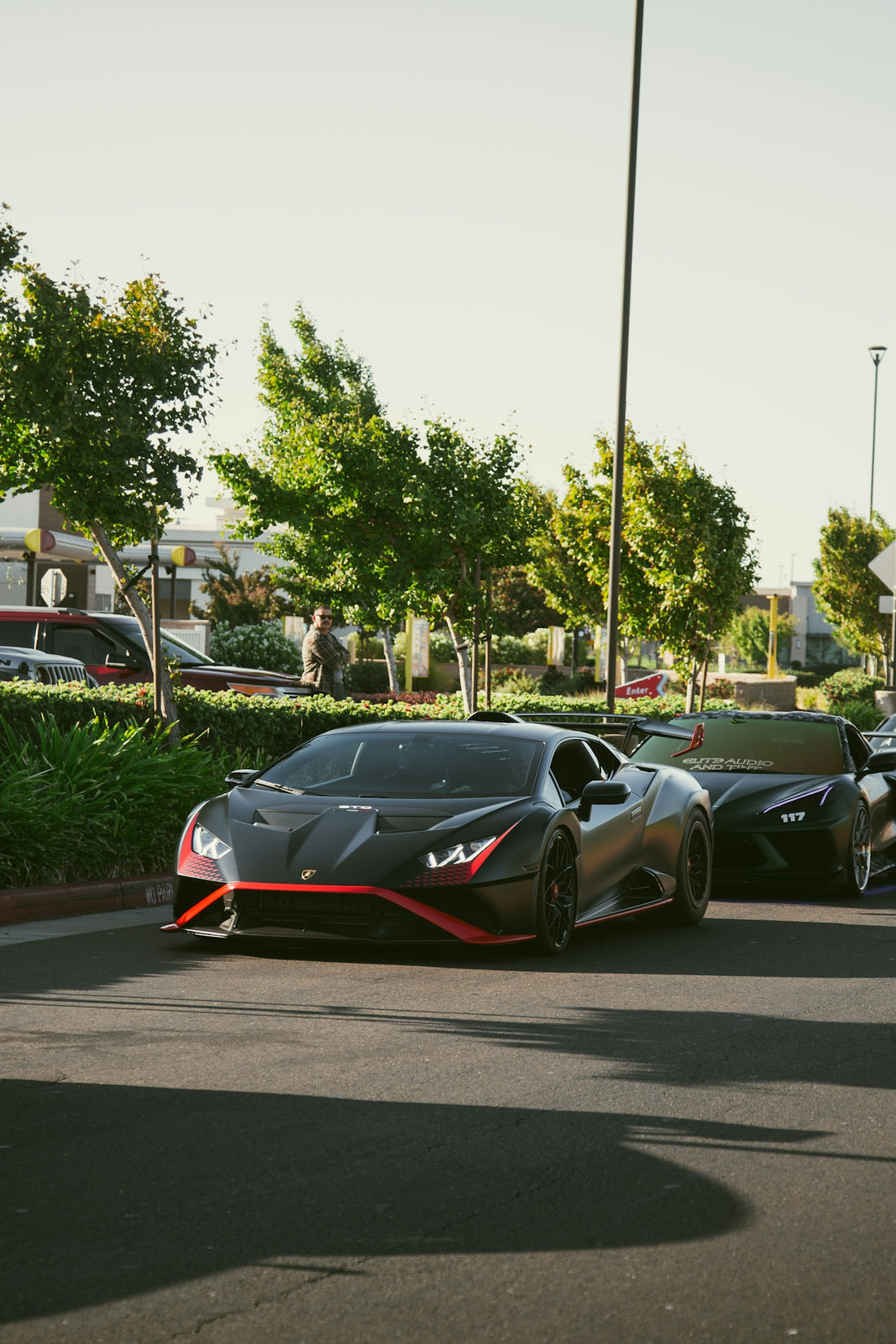 Two black sports cars parked in a row on an asphalt parking lot