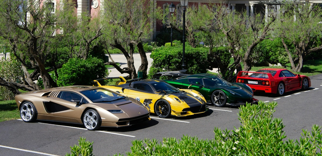 Four luxury sports cars parked in a row on an asphalt lot